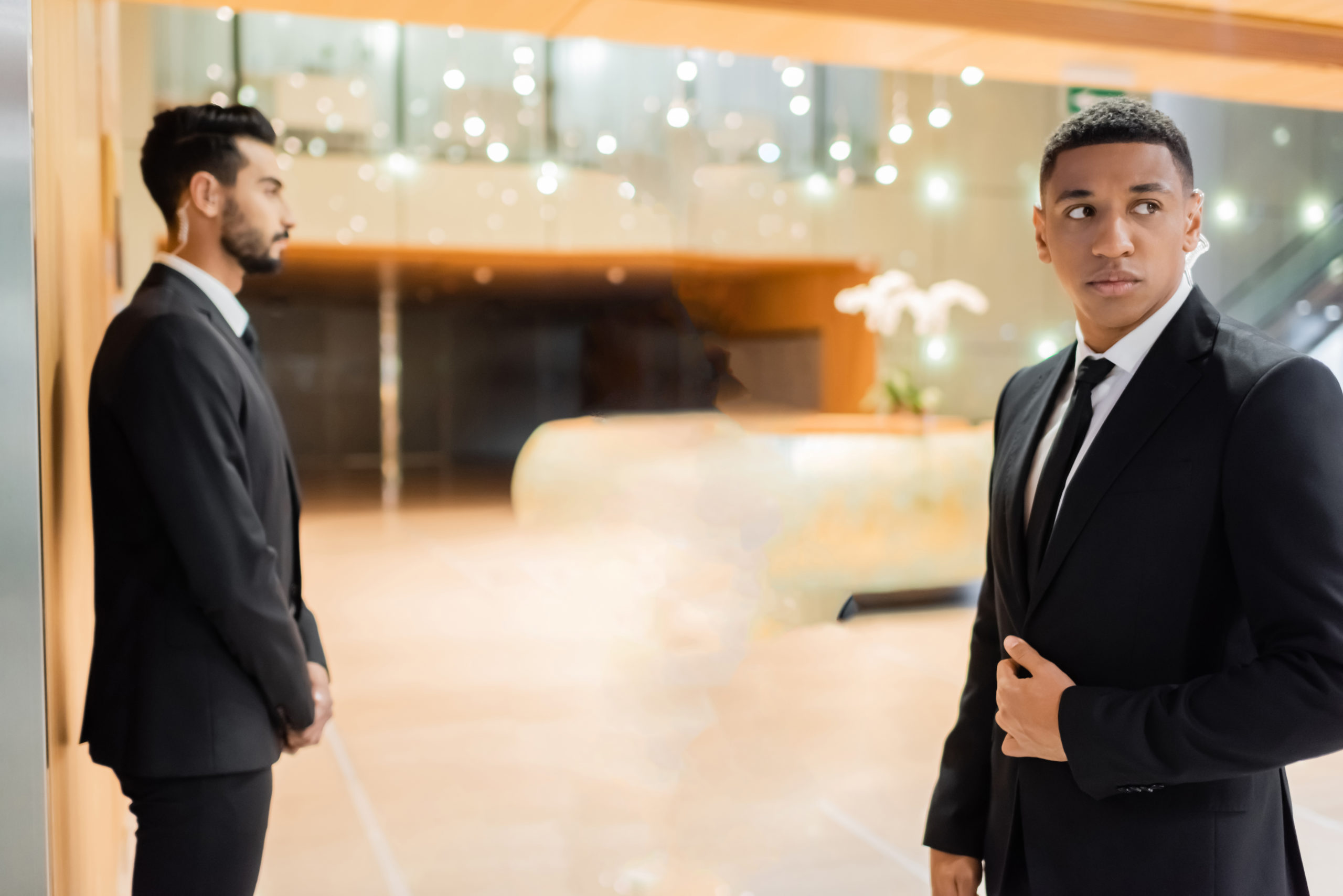 multiethnic guards escorting senior businesswoman in hotel foyer during business trip,stock image
